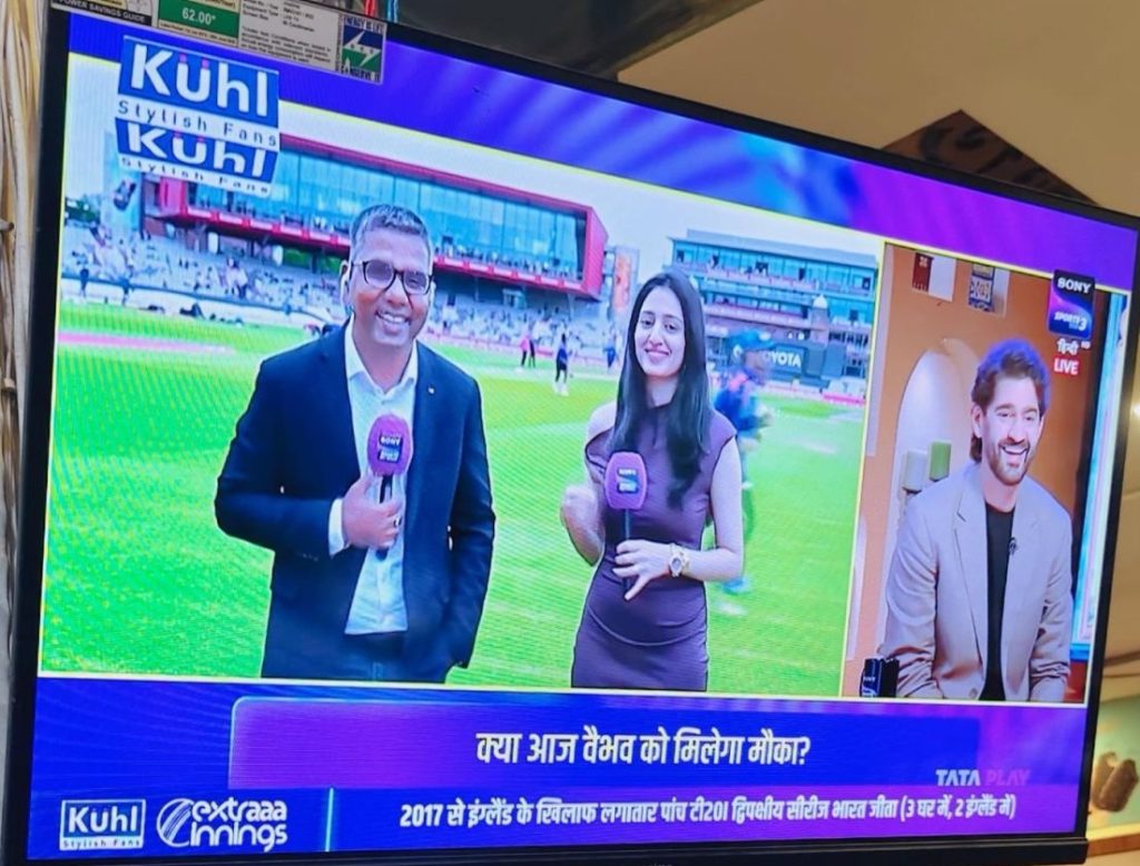 garima | No. 1 Indian Media News Portal TV broadcast of a sports talk show with two hosts standing on a cricket field, holding purple microphones; a guest appears in a split-screen on the right; Hindi captions run along the bottom.