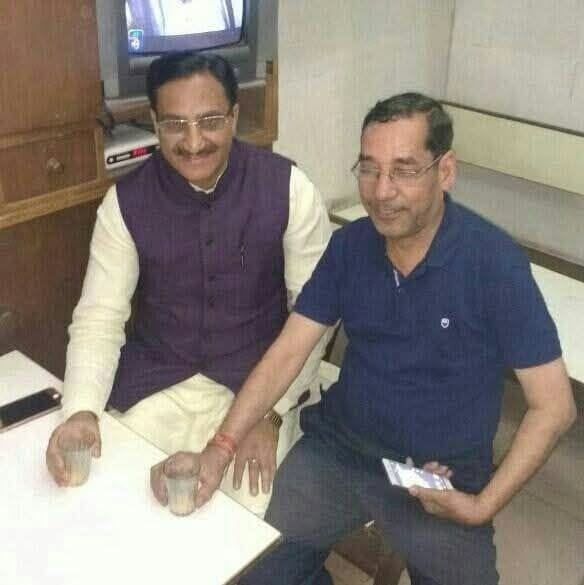 gopal rawat | No. 1 Indian Media News Portal Two men sit side by side at a small table, one in a purple vest and the other in a blue polo, each with a drink in hand.