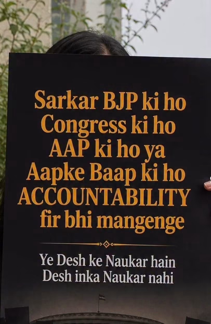 A protest sign in orange and white text demanding accountability from any party, held in front of a person outdoors.