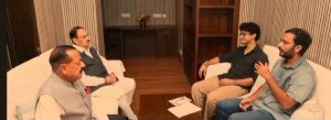 img_0014 | No. 1 Indian Media News Portal Four men sit on white sofas facing each other in a wood-paneled room, engaged in a discussion with papers on the coffee table.