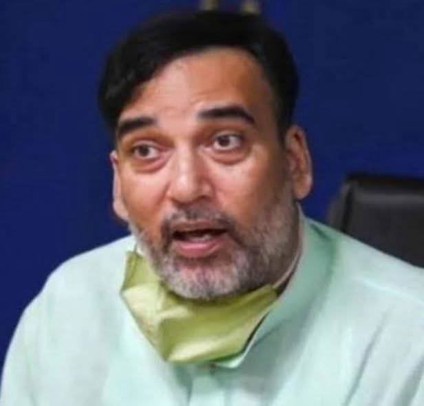 img_9448 | No. 1 Indian Media News Portal Bearded man in a light green kurta speaking, with a pale yellow mask resting under his chin, against a dark blue background.