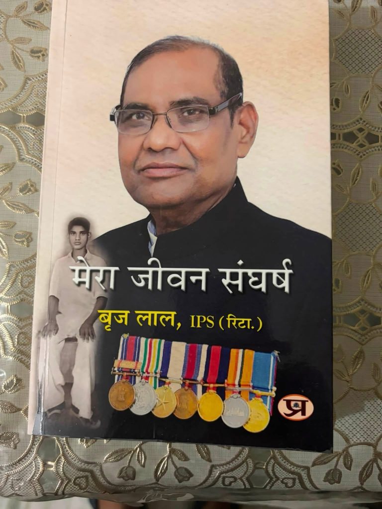 img_9498 | No. 1 Indian Media News Portal Book cover showing an adult man with glasses and a black outfit; smaller black-and-white photo of a younger man on the left; a row of colorful medals at the bottom; Hindi text title across the middle.
