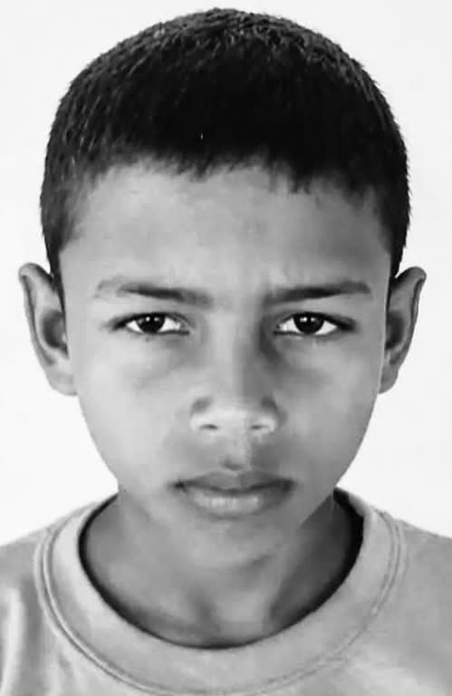 Close-up black-and-white portrait of a young boy looking straight ahead with a neutral expression.
