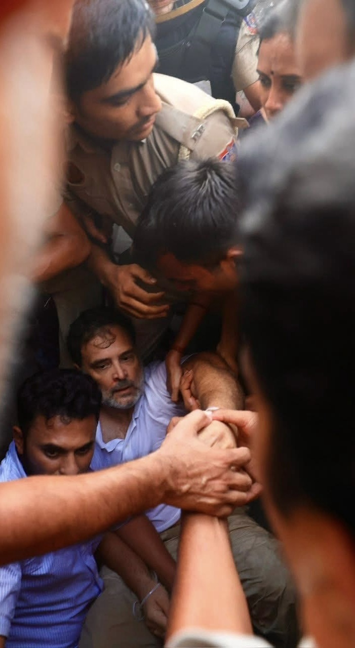 Crowded scene of men helping a man on the ground, several arms grip his limbs in a tense moment.