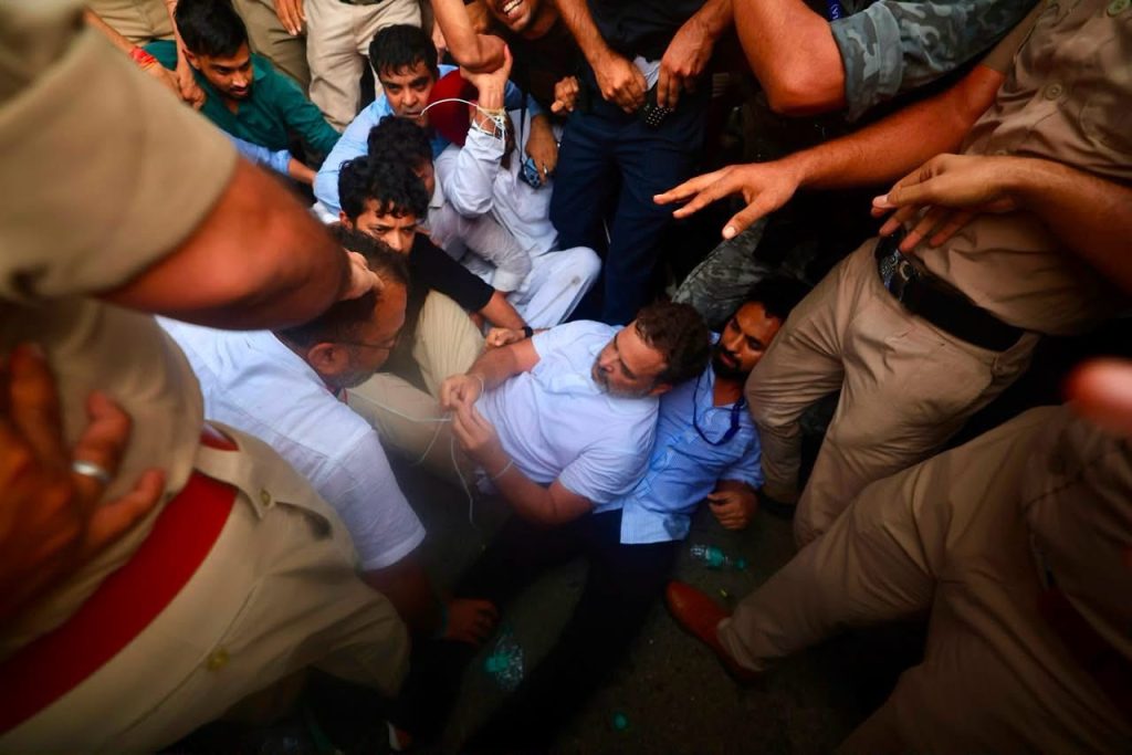 img_9870 | No. 1 Indian Media News Portal Man in a light blue shirt restrained by a crowd of uniformed men in a tight circle.