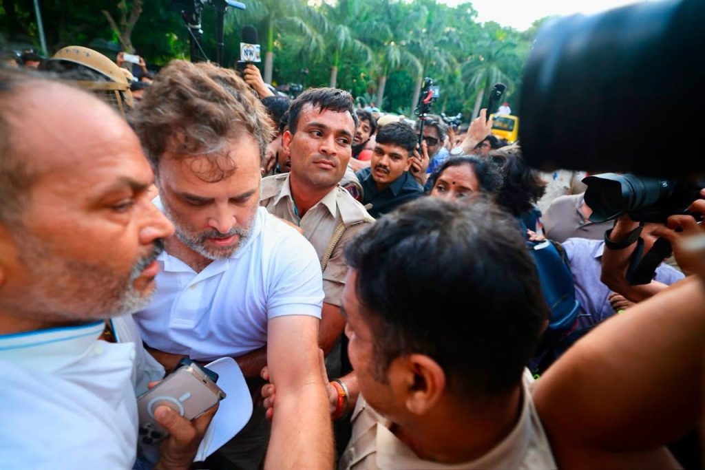 img_9873 | No. 1 Indian Media News Portal Crowded scene of journalists and security surrounding a man in a white polo shirt during a media scrum.