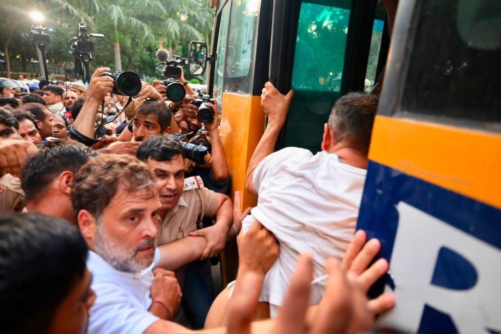 img_9874 | No. 1 Indian Media News Portal Crowded scene of reporters and photographers surrounding a yellow bus, filming and pushing to get closer to the door.