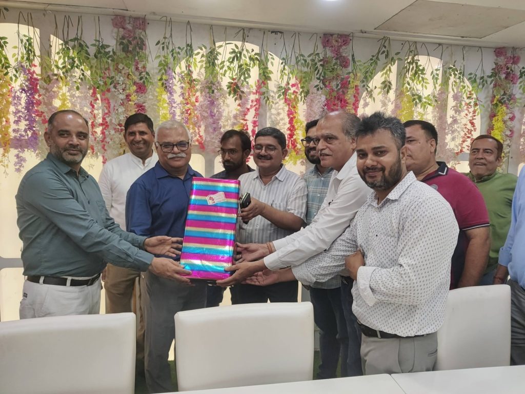 indu shekhar_1 | No. 1 Indian Media News Portal Group of men passing a large colorful wrapped gift at a celebration, with hanging flowers in the background.