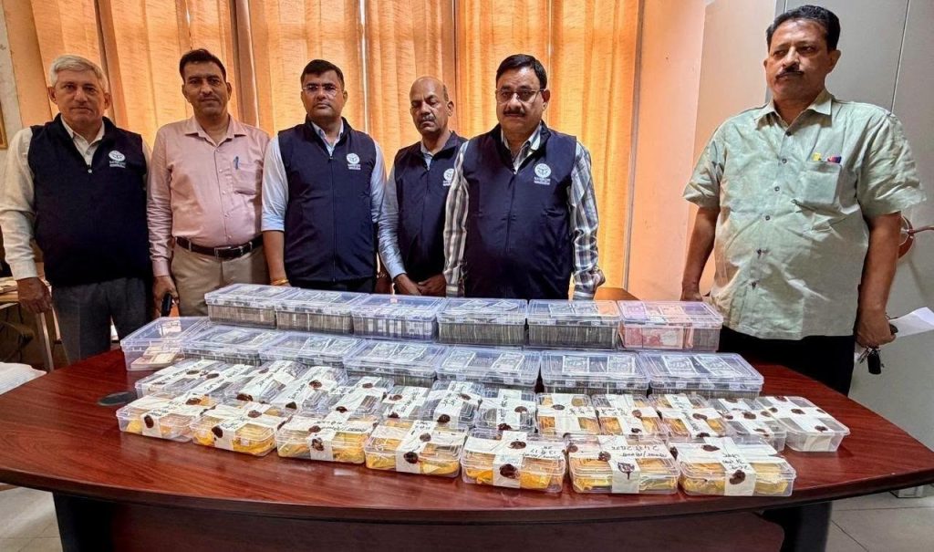 lalit k raid | No. 1 Indian Media News Portal Group of six men standing behind a table filled with clear plastic containers containing bundles of currency, likely a seizure display.