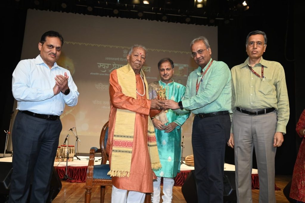 lokarpan_2 | No. 1 Indian Media News Portal Group of men on a stage presenting a trophy to one honoree in orange traditional attire while others applaud and look on in a formal ceremony setting.
