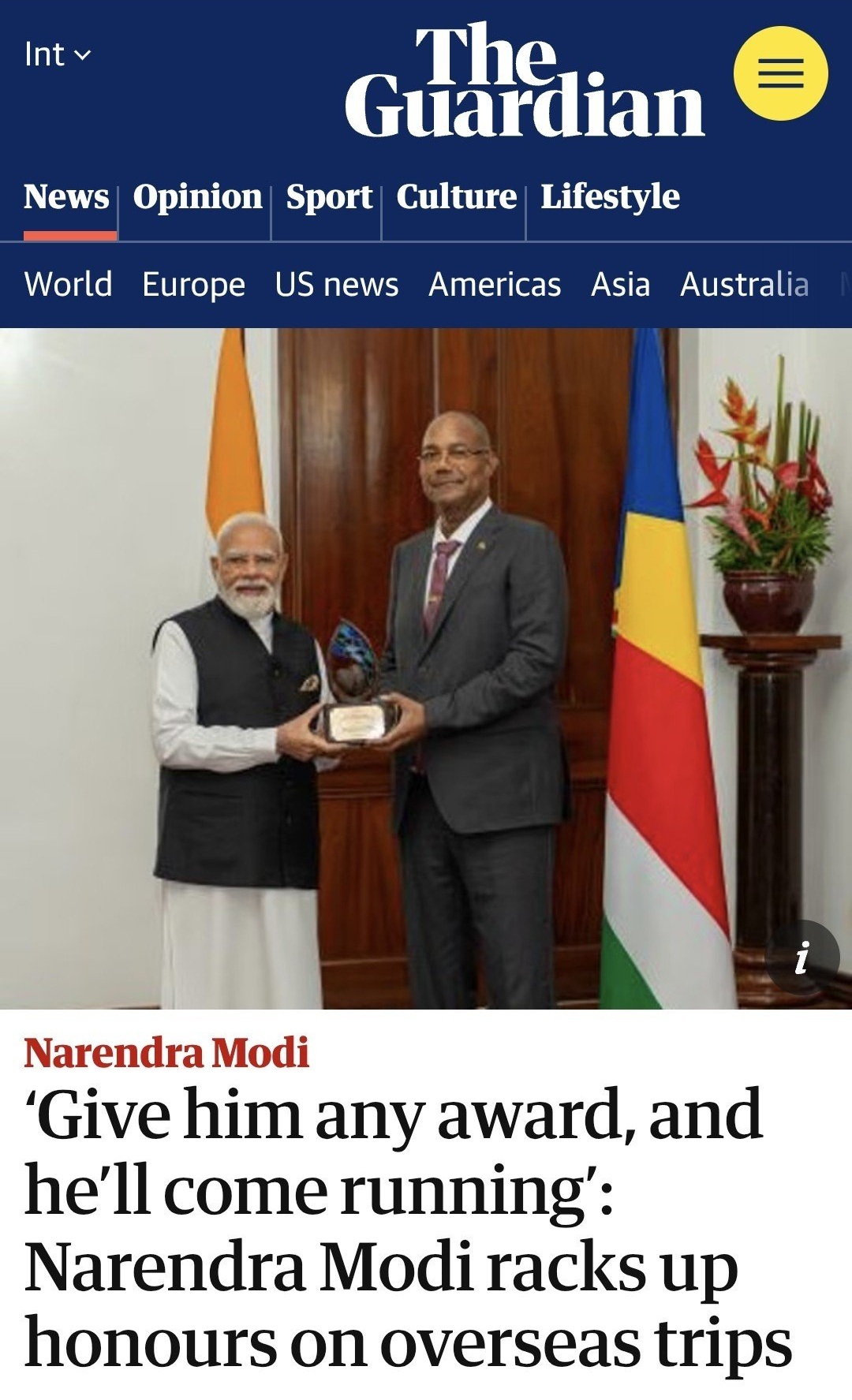 Two men in formal attire exchange a glass award in a ceremonial setting, with national flags in the background.