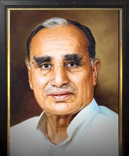 Portrait of an elderly man with white hair and thick eyebrows, wearing a light shirt, framed in a dark wood frame.