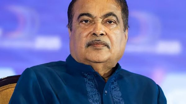 Portrait of a man with a mustache wearing a dark blue embroidered kurta, facing the camera against a blue backdrop.