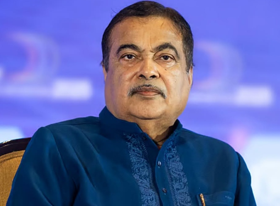 Portrait of a man with a mustache wearing a dark blue embroidered kurta, facing the camera against a blue backdrop.