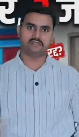 omer | No. 1 Indian Media News Portal Man with a mustache wearing a light blue striped shirt faces the camera indoors, with posters or signage visible in the background.