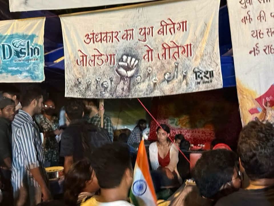pratirodh | No. 1 Indian Media News Portal Crowd of people at a protest or rally under large banners with a raised fist illustration and Hindi text; an Indian flag is in the foreground.