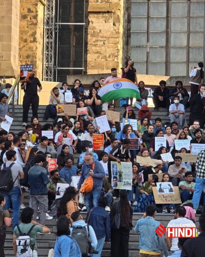 protest | No. 1 Indian Media News Portal Group of people gathered on outdoor steps holding protest signs and an Indian flag, facing forward during a daylight demonstration at a public square.