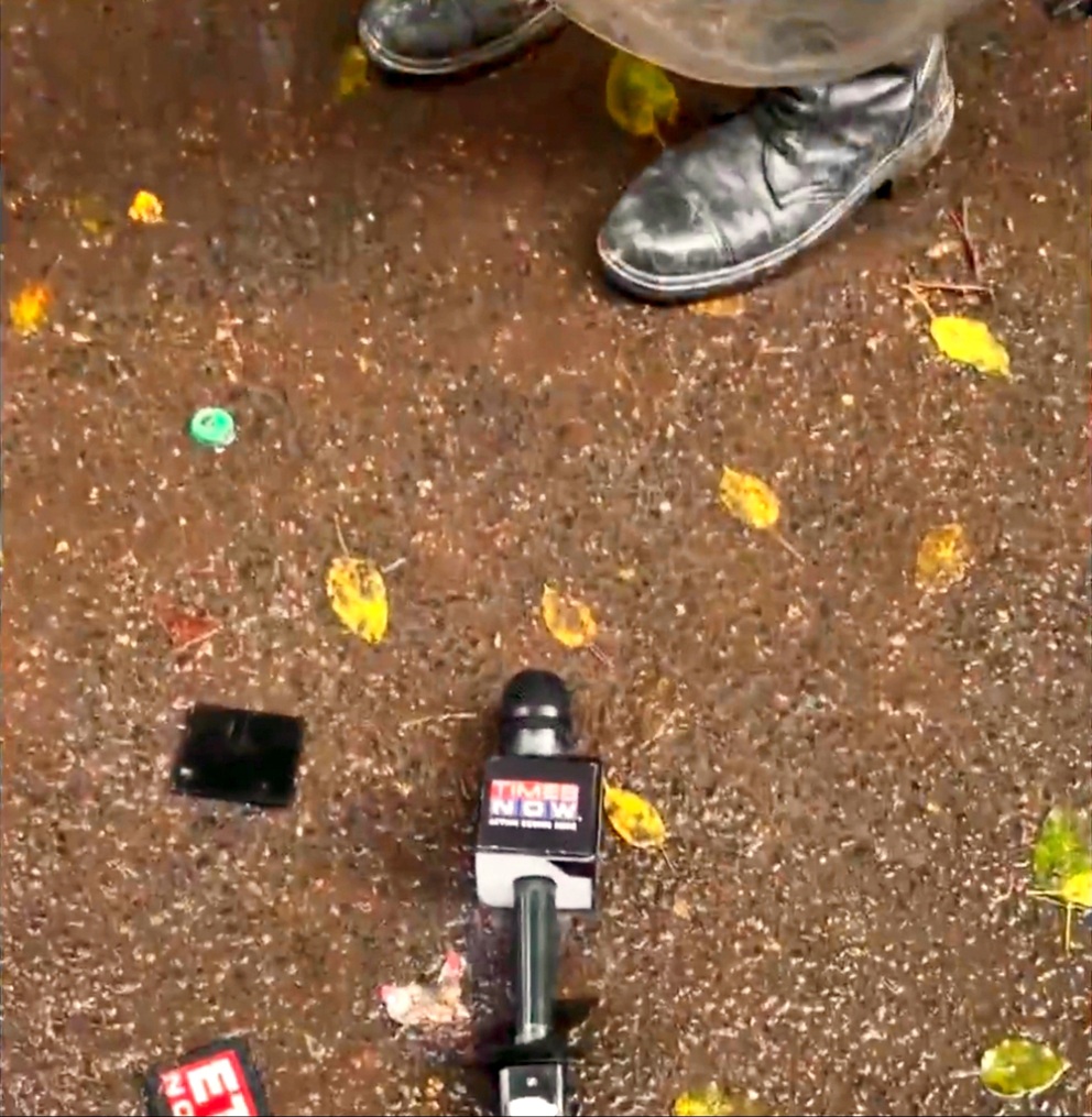 Broadcast microphone lying on wet pavement among yellow leaves, with a shoe visible in the background.