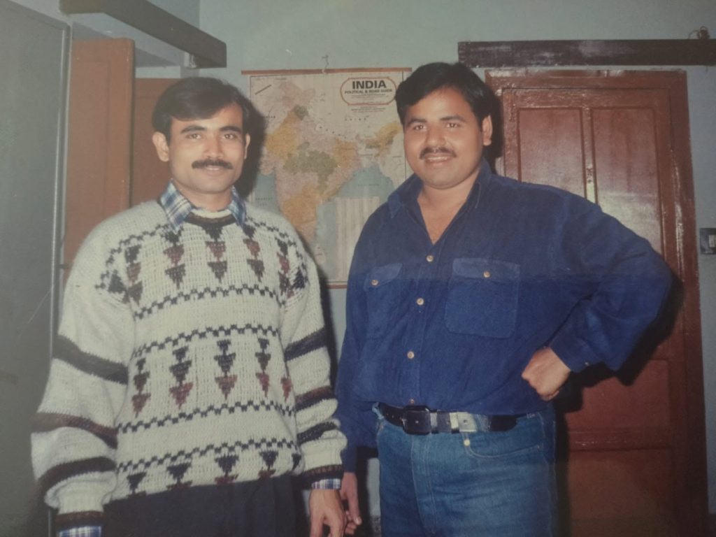 sanjaydixit | No. 1 Indian Media News Portal Two men pose for a photo indoors, one in a patterned knit sweater and the other in a blue denim shirt, both smiling.