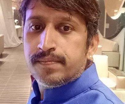 Portrait of a man with a blue kurta in an indoor lounge, looking at the camera.