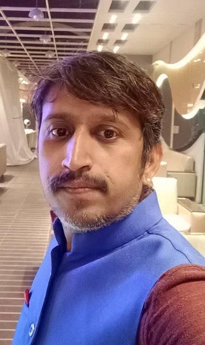 Portrait of a man with a blue kurta in an indoor lounge, looking at the camera.