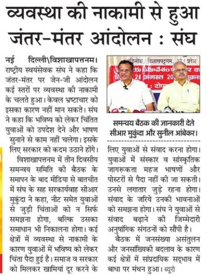 Hindi newspaper clipping about a Jantar-Mantar protest; two men speak at a press meet with a red banner in the background.