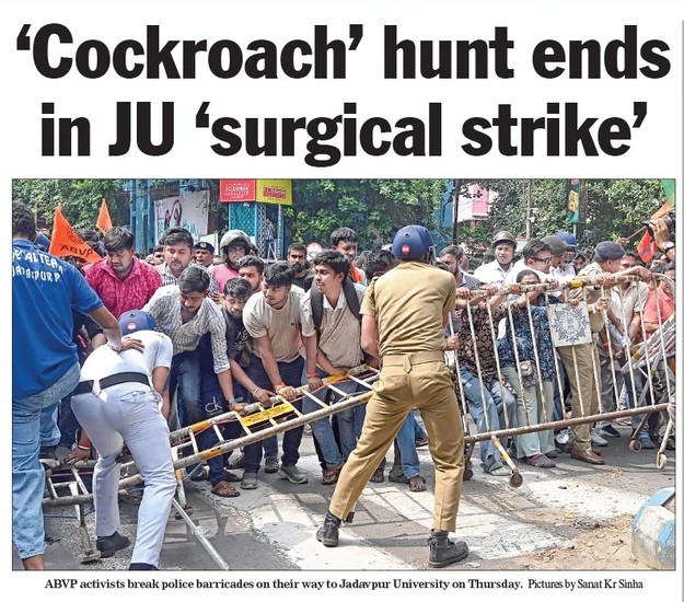 Crowd of protesters pushes against metal barricades as a police officer in khaki maintains a line, during a confrontation near Jadavpur University.
