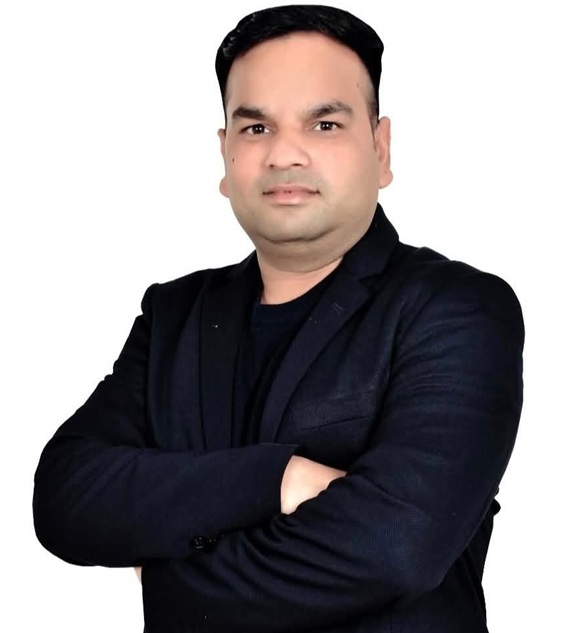 Professional portrait of a man in a dark blazer with arms crossed against a white background.