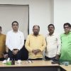 Group of professionals standing around a conference table in a meeting room, posing for a photo.