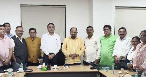 Group of professionals standing around a conference table in a meeting room, posing for a photo.