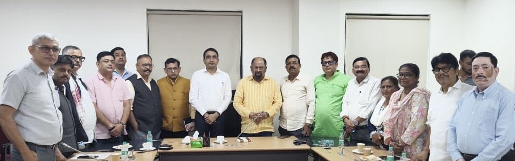 Group of professionals standing around a conference table in a meeting room, posing for a photo.