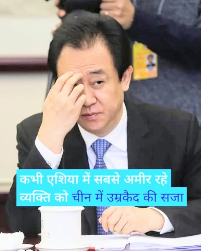 Man in a dark suit at a meeting rubs his eye, with a blue Hindi caption banner across the bottom.