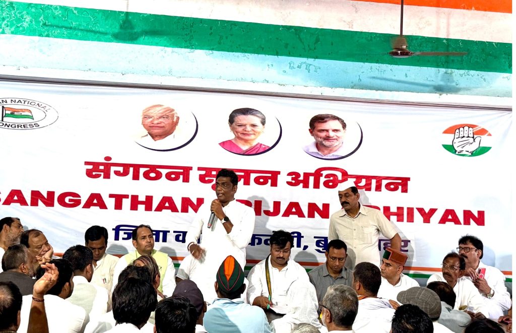 congress_bs_1 | No. 1 Indian Media News Portal Male speaker in white kurta addresses a crowd at a political event, banner with Congress symbols behind him.