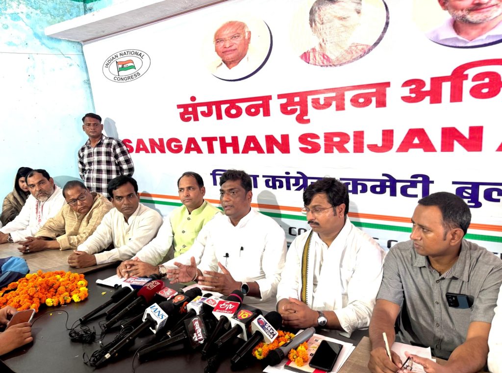 congress_bs_2 | No. 1 Indian Media News Portal Group of men at a press conference seated at a table with multiple microphones, a large banner with Hindi text behind them.