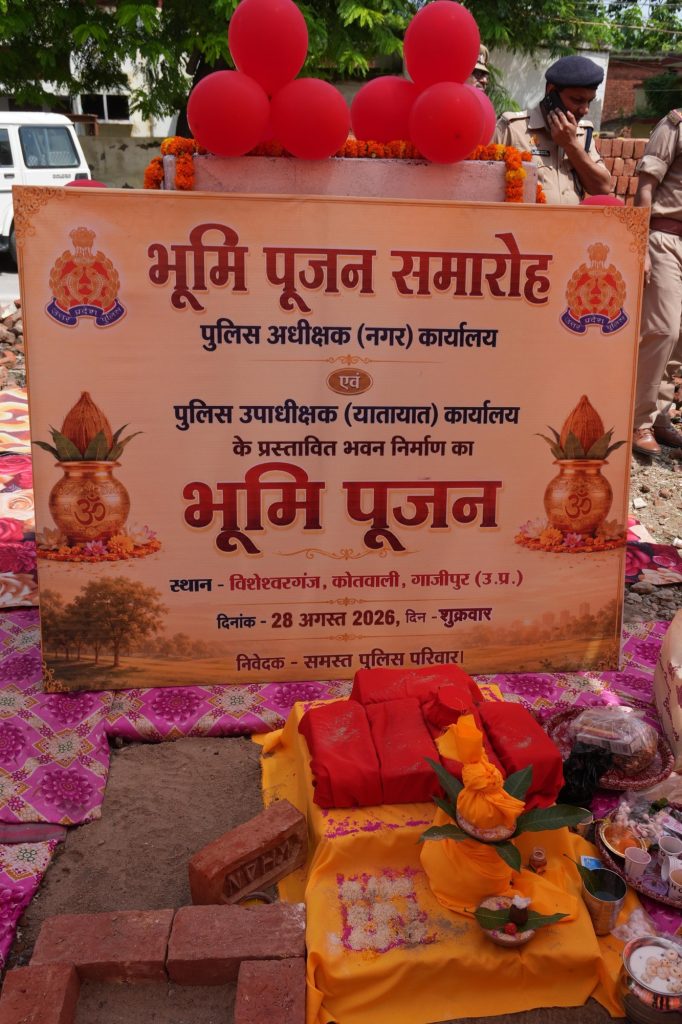 d0bc3988-509e-4a1f-89bb-9492b8d612f6 | No. 1 Indian Media News Portal Ceremonial Bhoomi Poojan display with orange banner, marigold garlands, red balloons, and ritual items on yellow cloth.