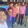 Group of seven people posing for a selfie outdoors, all smiling at the camera in a sunny courtyard area outside a building.