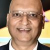 Smiling bald man wearing glasses and a dark suit, looking at the camera.