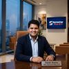 Daksh Kumar, CEO of Samachar Plus OTT, sits at a polished desk in a modern office, smiling at the camera.