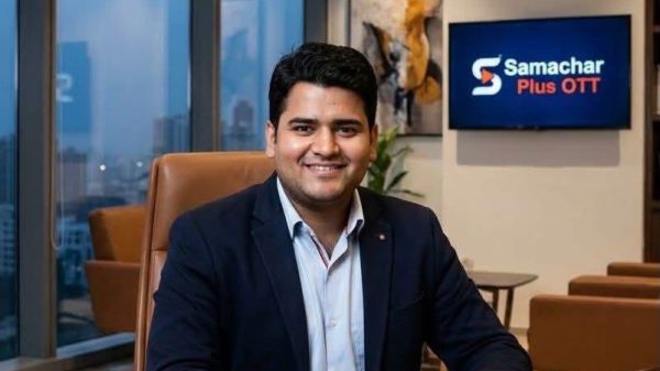 Daksh Kumar, CEO of Samachar Plus OTT, sits at a polished desk in a modern office, smiling at the camera.