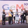 Group of men on stage during GeM 10 awards ceremony, exchanging a plaque with a backdrop displaying GeM 10 and ministry logos.