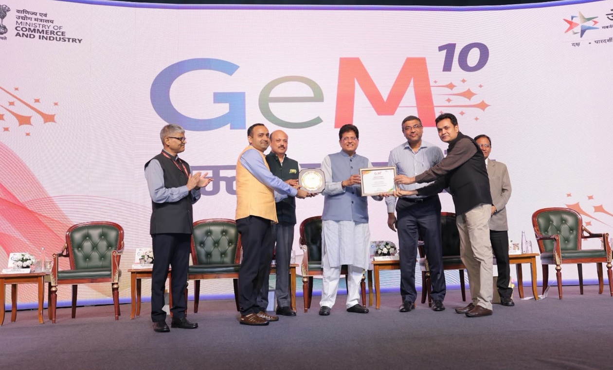 Group of men on stage during GeM 10 awards ceremony, exchanging a plaque with a backdrop displaying GeM 10 and ministry logos.