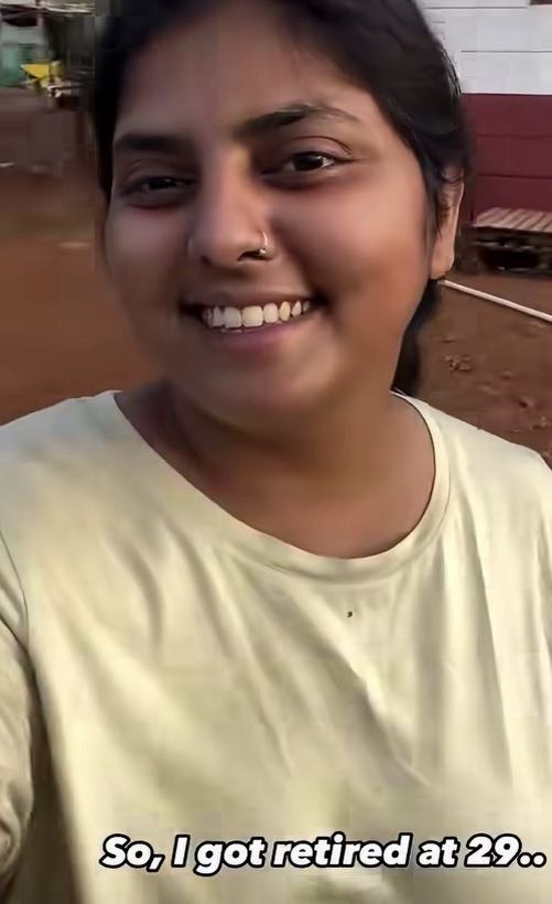 Smiling woman in a pale yellow shirt taking a selfie outdoors; caption reads: 'So, I got retired at 29..'
