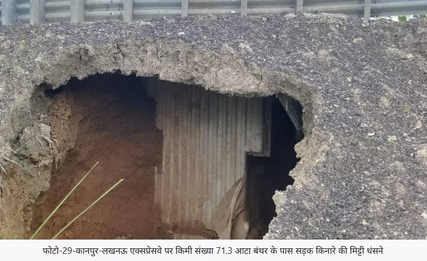 Roadway collapse visible: large hole in asphalt with exposed soil and a concrete wall beneath the road near a guardrail, suggesting a sinkhole.