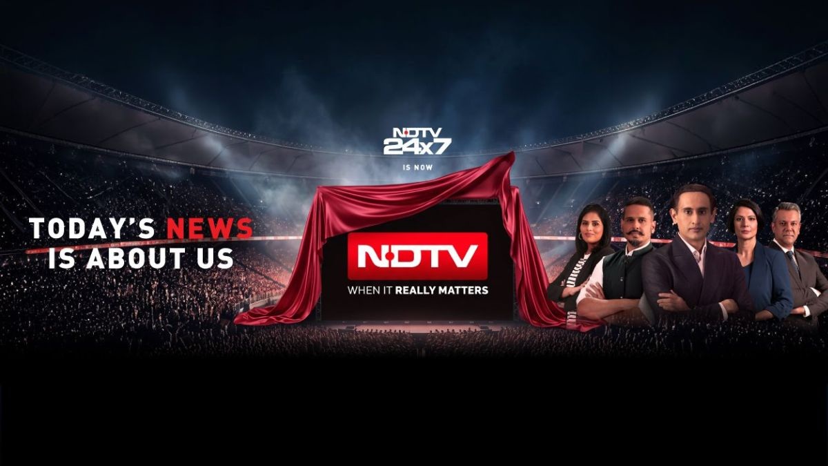 NDTV 24x7 illuminated studio stage with a red-draped screen revealing the NDTV logo and a team of anchors on the right, slogan: 'Today’s News Is About Us'.