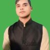 Portrait of a man wearing a black vest over a beige kurta against a solid green background.