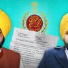 Two men in yellow turbans and beards pose against a teal backdrop, with a white document and an official seal between them.
