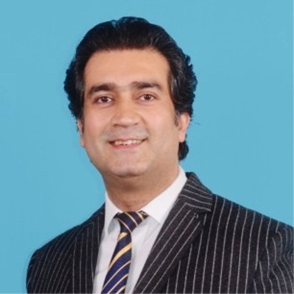 Professional portrait of a smiling man in a pinstripe suit against a light blue background.