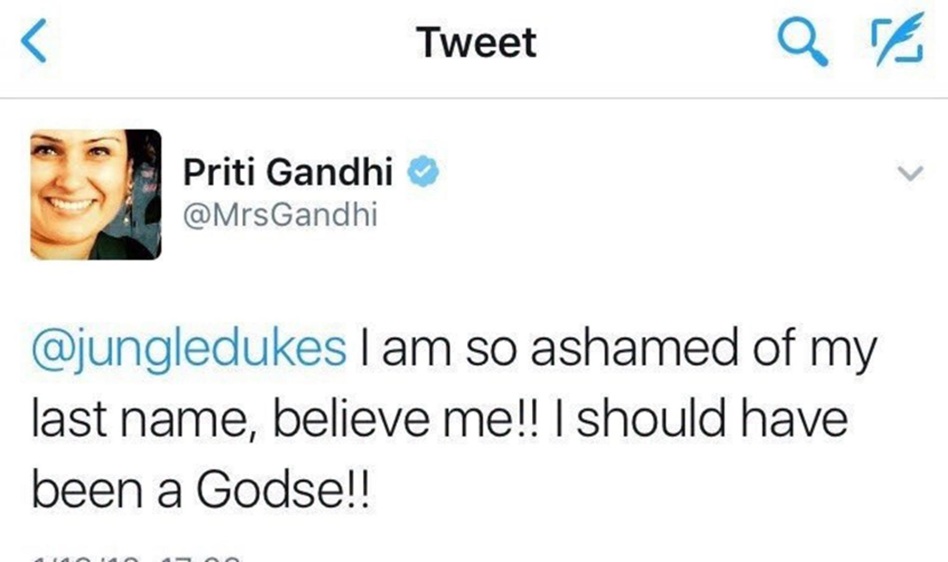Screenshot of a Twitter post: profile picture of a smiling woman, blue verified badge, text reads "@jungledukes I am so ashamed of my last name, believe me!! I should have been a Godse!!"