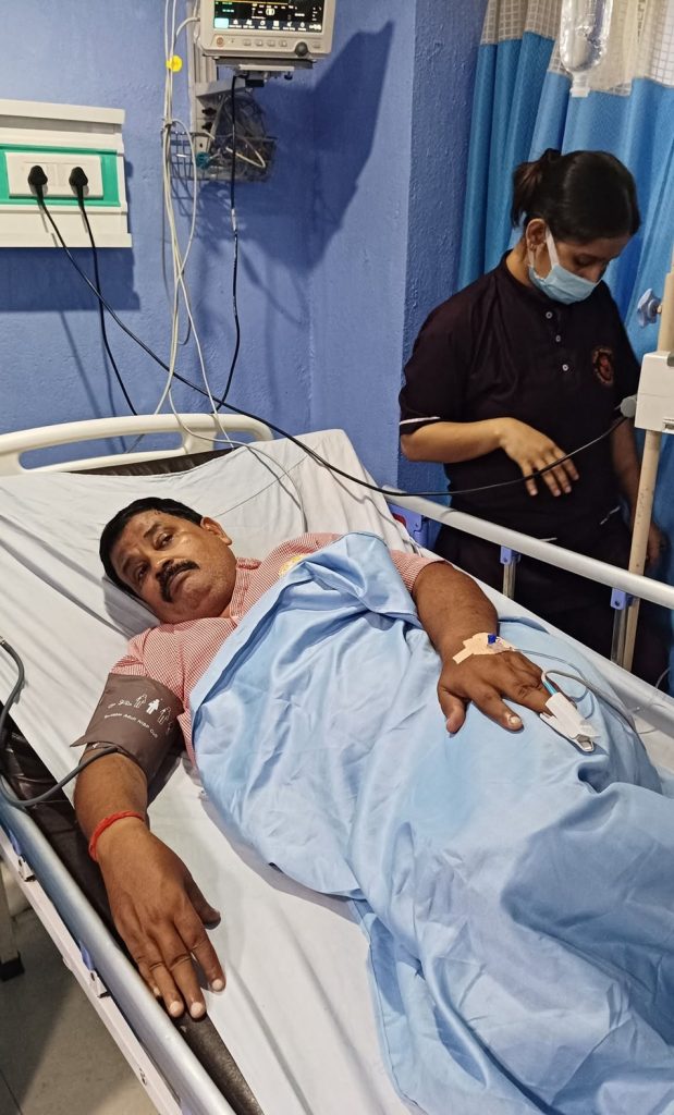 rajkumar | No. 1 Indian Media News Portal Hospital patient lying in bed connected to monitors and IV lines with a nurse in the background adjusting equipment.