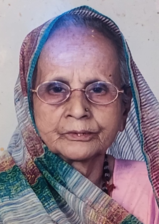Portrait of an elderly woman wearing a multicolor headscarf and round glasses, looking at the camera.
